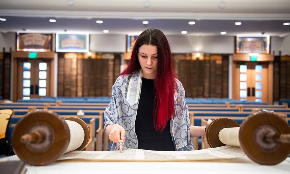 girl reading a torah scroll