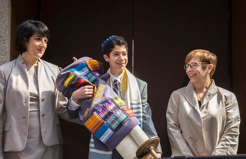boy outside synagogue holding torah