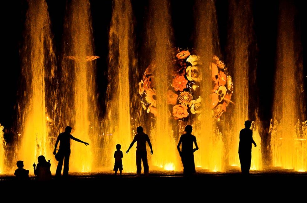 people standing by a colored fountain at night