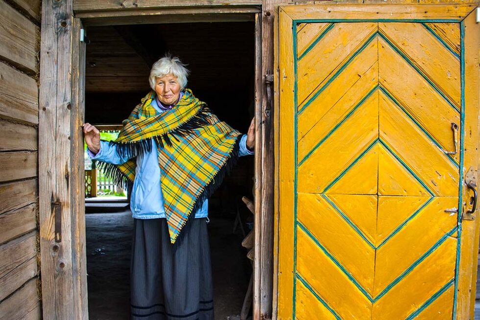 older woman smiling in a brightly painted doorway