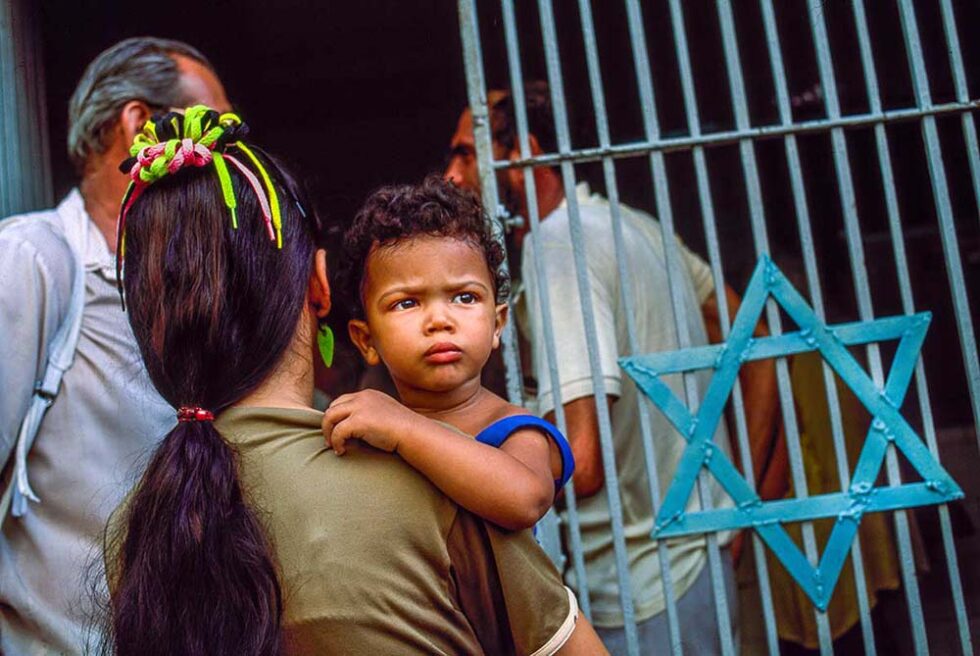 woman holding her son by a gate with a star of david in cuba